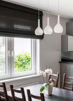 Roman shade style window blinds help frame this beautiful kitchen with orchids on the table