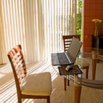 Vertical blinds by Oregon Blinds hang in front of a patio door in this home office