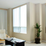 Open and closed sets of vertical blinds from Oregon Blinds show versatility in this warm living room